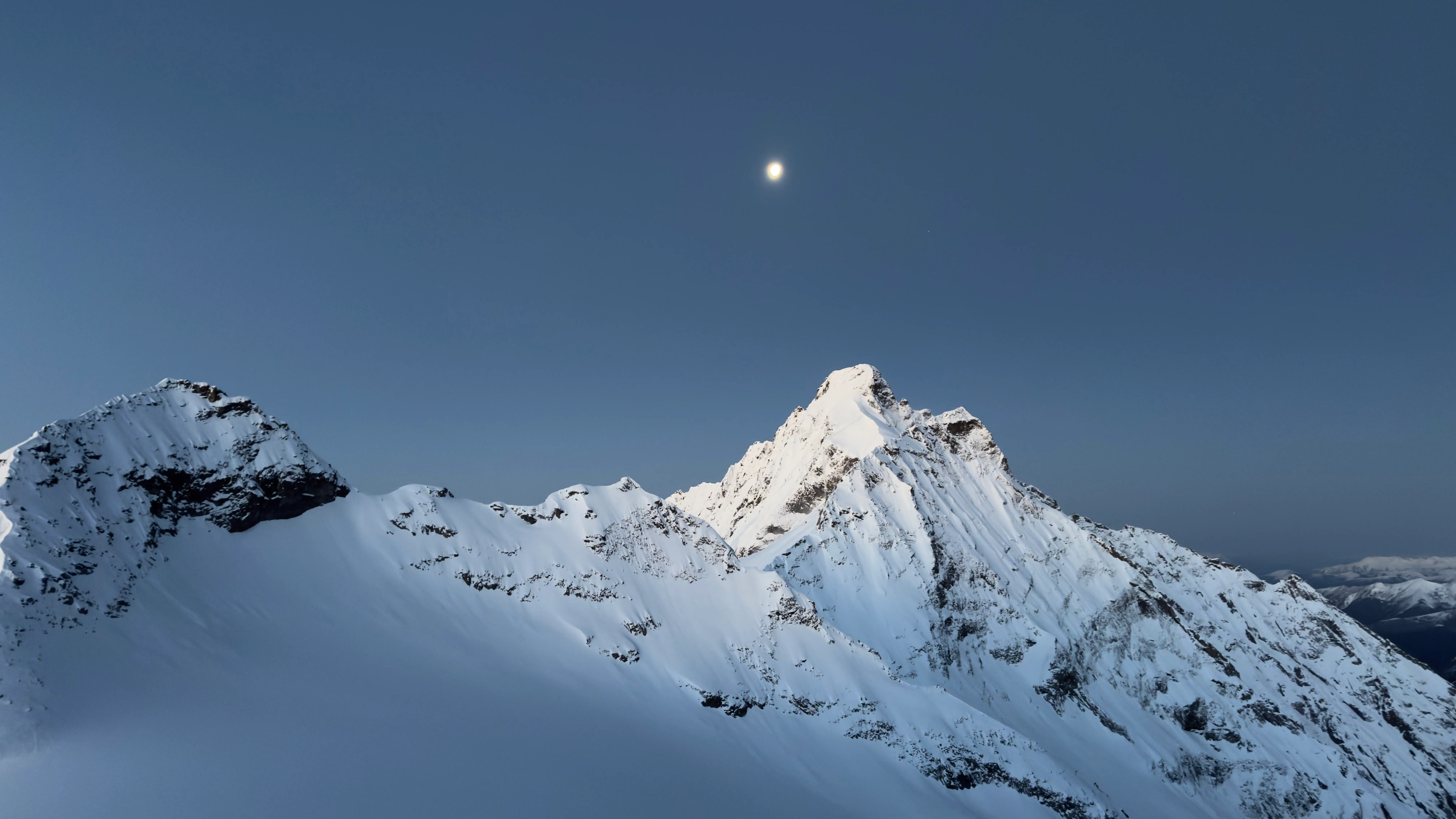 Moonrise over snow-capped peak